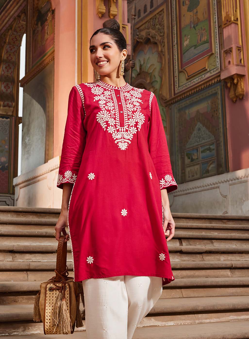 A woman wearing a vibrant and colorful 3/4th sleeve dress with floral patterns and a flowing silhouette