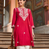 A woman wearing a vibrant and colorful 3/4th sleeve dress with floral patterns and a flowing silhouette