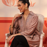 A woman standing wearing a Niya Oak Brown Embroidered Cotton Linen Slub Long Top with a V-neckline