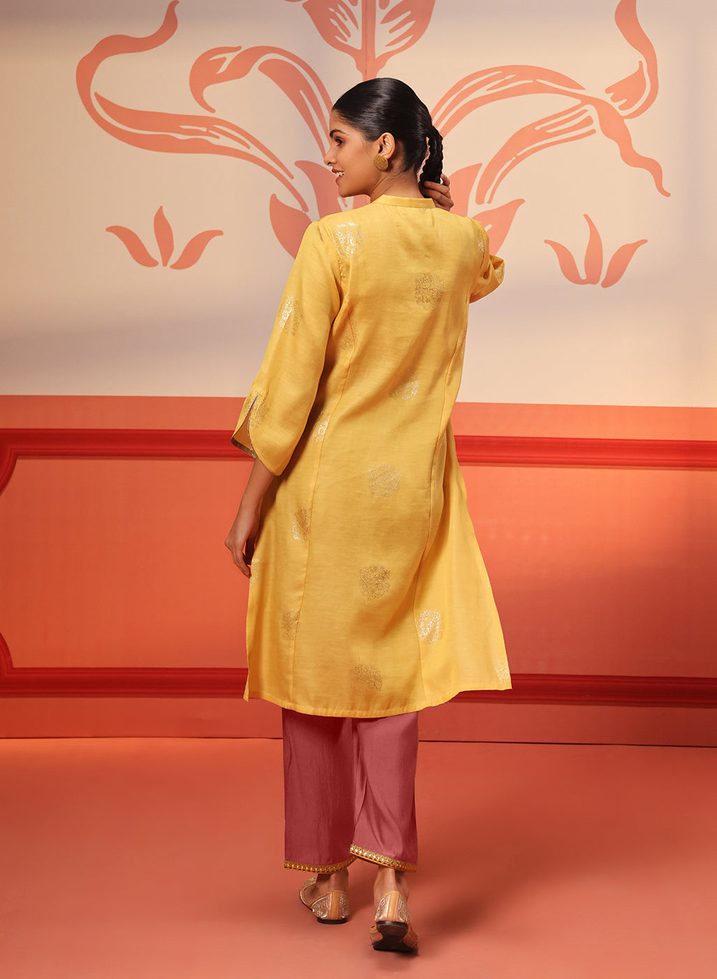 Woman walking away in Rumi Bright Yellow Printed Tunic Set paired with embroidered pumps