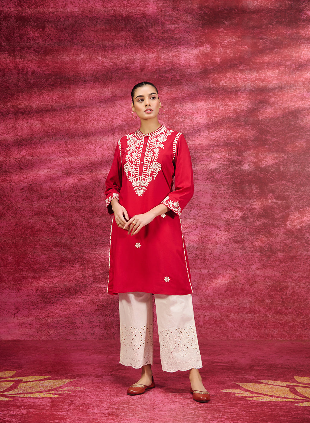 A woman wearing a Saadgi Red Embroidered Cotton Linen Tunic along with a white palazzo