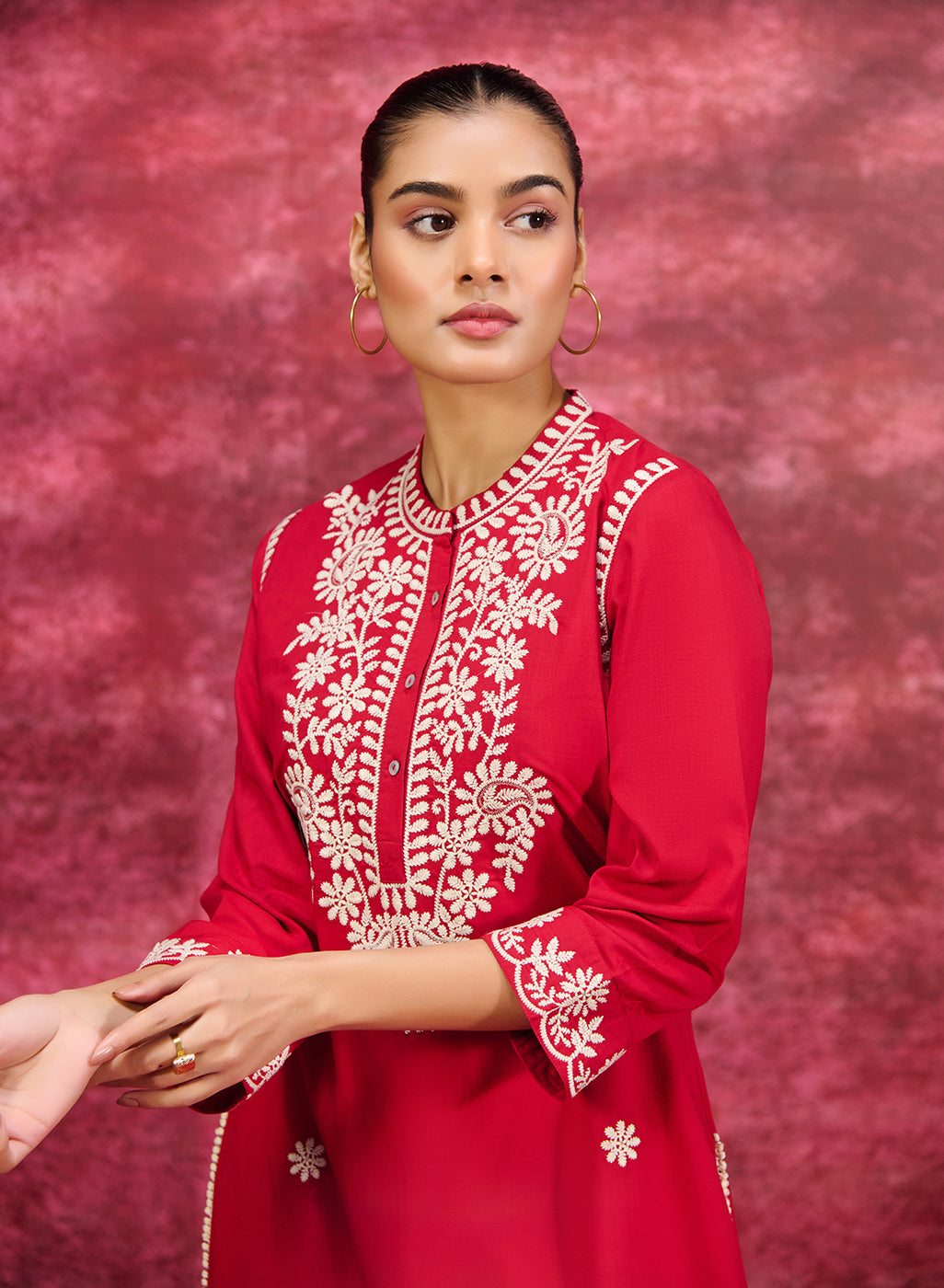 A stylish woman wearing an elegant Saadgi red cotton linen tunic with white embroidery on front and sleeves